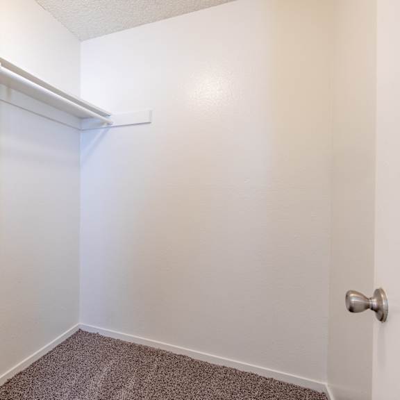 an empty closet in a room with white walls and carpet