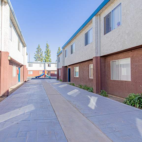 an empty alley between two buildings with a blue sky