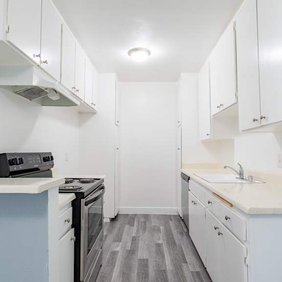 a kitchen with white cabinets and a stove and a sink