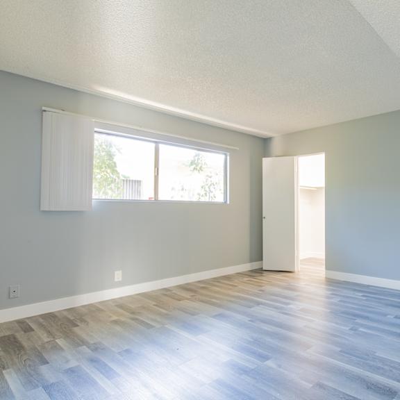 an empty living room with wood floors and a window