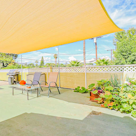 a patio with chairs and a table under a canopy