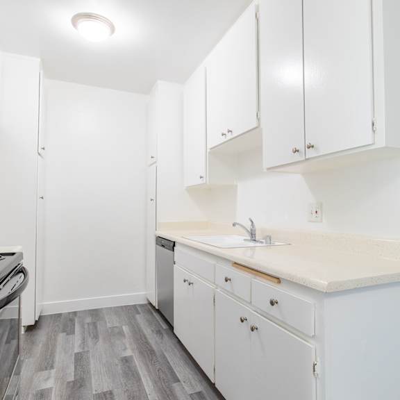 a white kitchen with white cabinets and a stove and sink