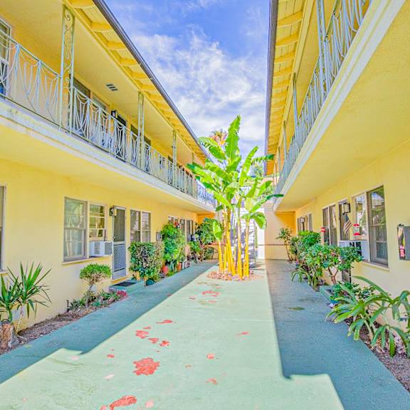 a courtyard between two yellow buildings with a blue walkway