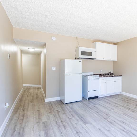 an empty kitchen with white appliances and a microwave and refrigerator
