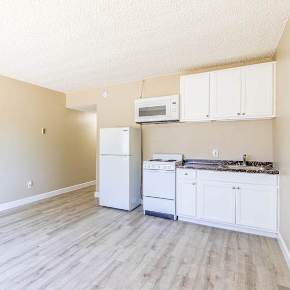 an empty kitchen with white appliances and white cabinets