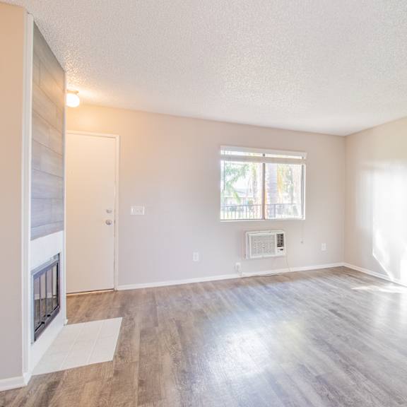 an empty living room with a fireplace and a window