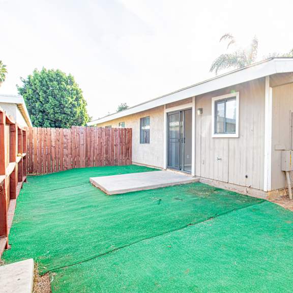 the backyard has a green lawn and a small house