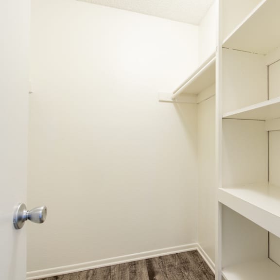 a walk in closet with white shelves and a door