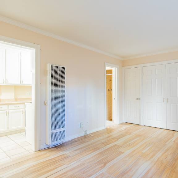 an empty living room with white doors and a wood floor