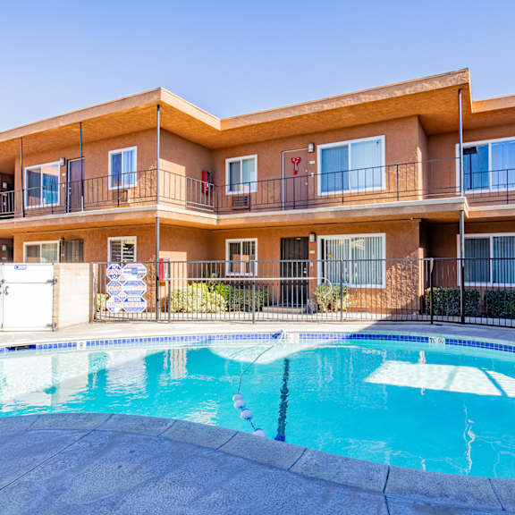 a swimming pool in front of a multi-story apartment building.
