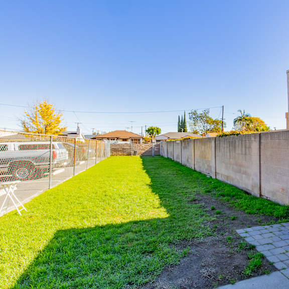 a yard with a fence and a green lawn next to a parking meter