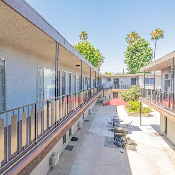 a long balcony with tables and chairs at a building with windows