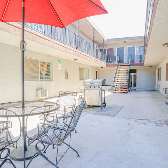 a patio with a table and chairs and a red umbrella