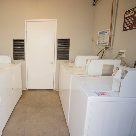 a row of washing machines in a room with a door