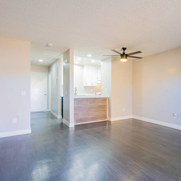 an empty living room with wood floors and a ceiling fan