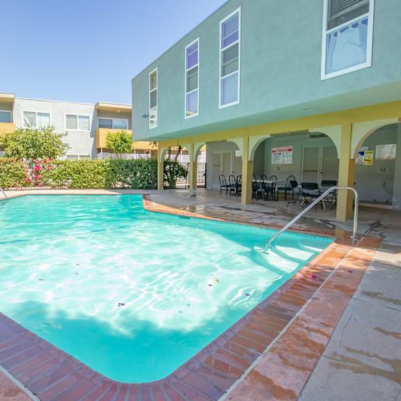 a swimming pool in front of a building with a resort style pool