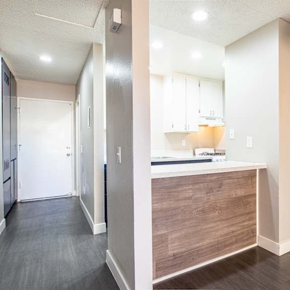 a renovated kitchen with white cabinets and wood flooring and a hallway with a door