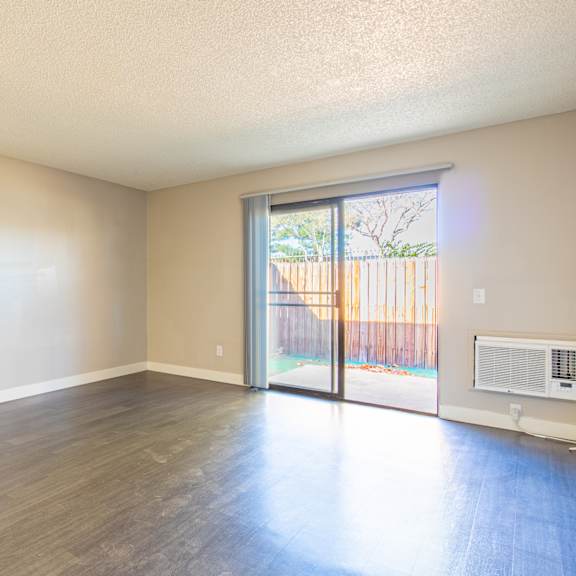 an empty living room with a sliding glass door to a patio
