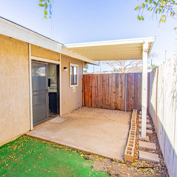 the front yard of a house with a patio and a backdoor to a yard