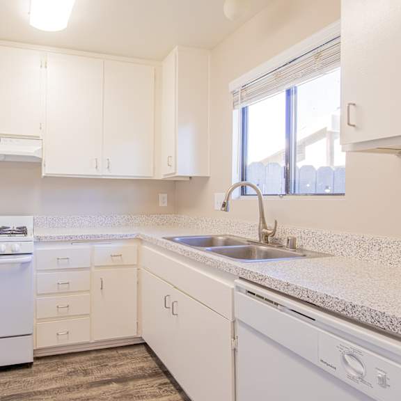 a kitchen with white cabinets and a sink and a window