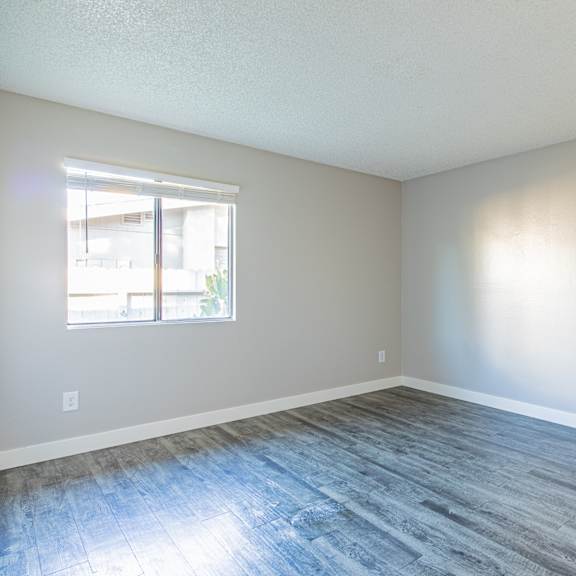 an empty room with wood floors and a window