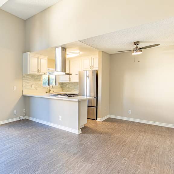 an empty living room with a kitchen and a sliding glass door