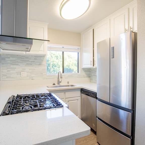 an updated kitchen with stainless steel appliances and white countertops