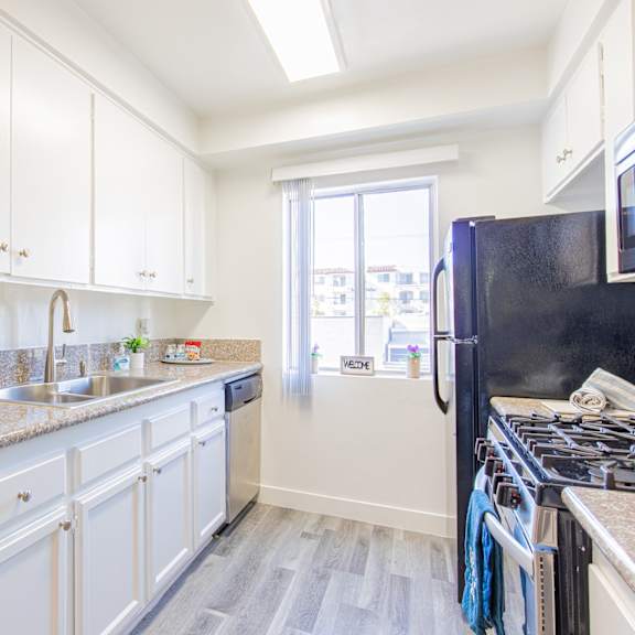 a kitchen with white cabinets and granite counter tops and a black stove and refrigerator