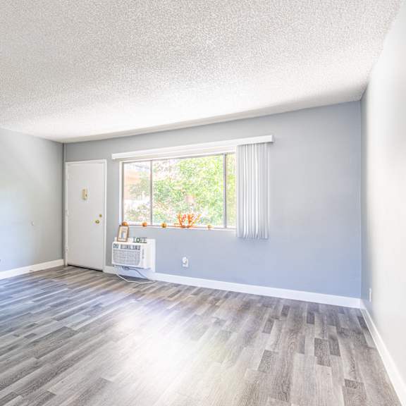 an empty living room with wood floors and a window