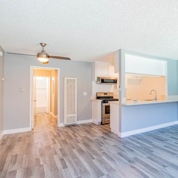 an empty living room and kitchen with a hard wood floor