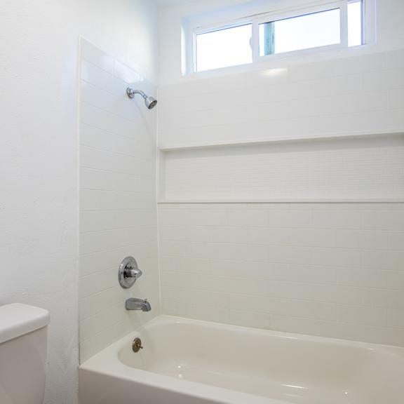 a bathroom with a tub and a toilet and a window