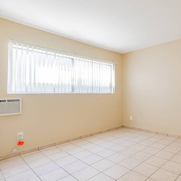 an empty room with a window and a tiled floor