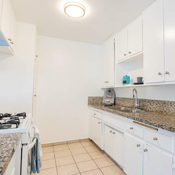a kitchen with white cabinets and granite counter top and a stove