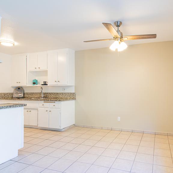 an empty kitchen with a ceiling fan and a window