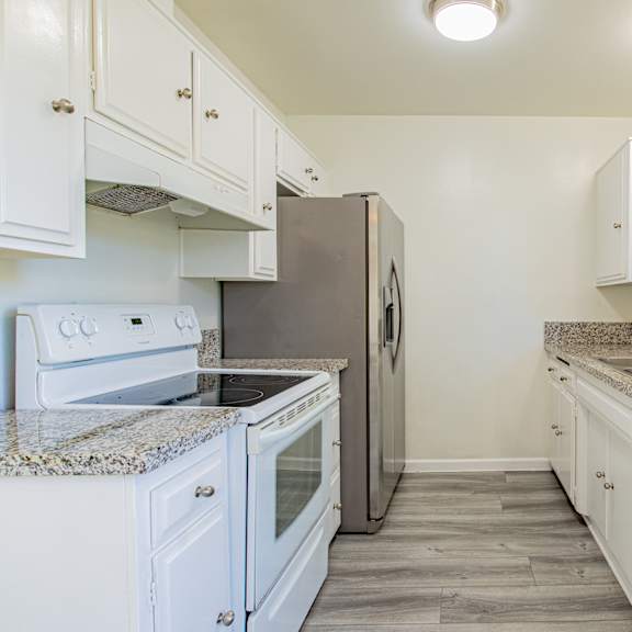 an empty kitchen with white appliances and granite counter tops
