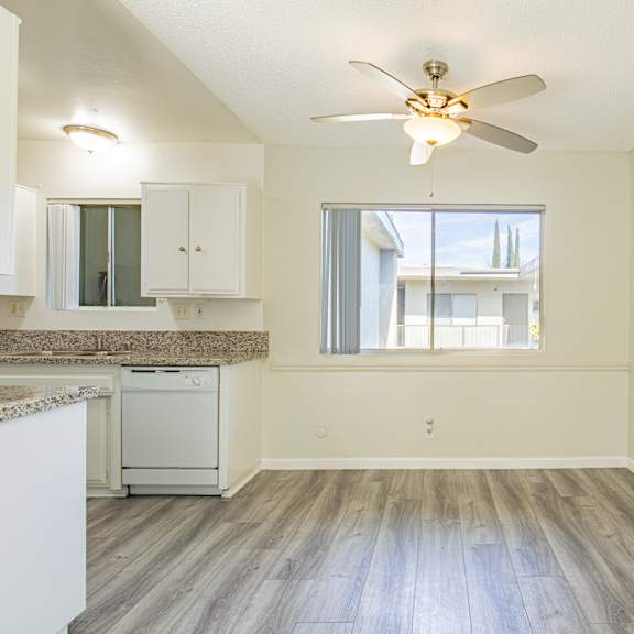 an empty kitchen with a ceiling fan and a window