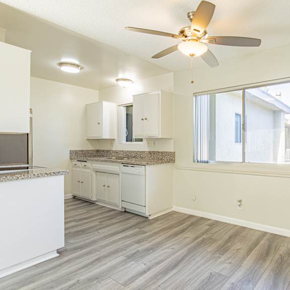 an empty kitchen and living room with a ceiling fan
