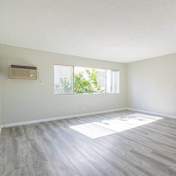 an empty living room with wood floors and a window