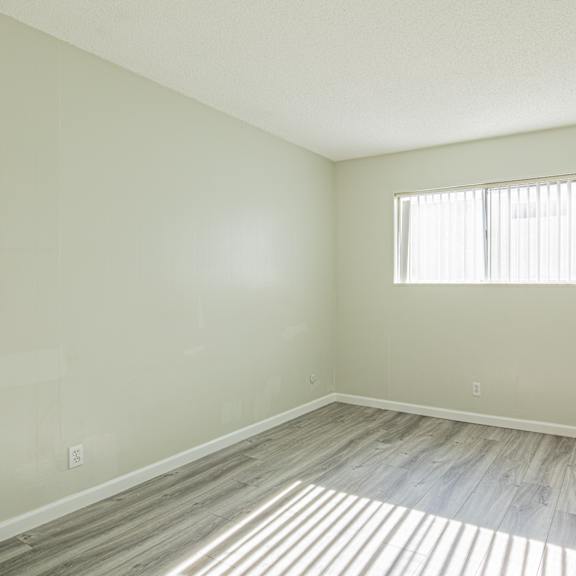 an empty room with wood floors and a window
