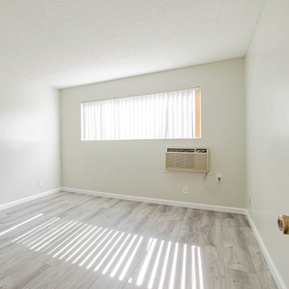 an empty living room with wood flooring and a window
