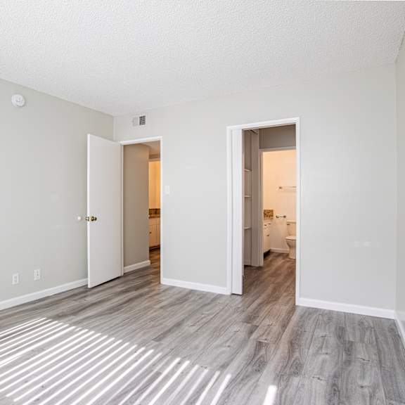 a spacious living room with white walls and wood flooring