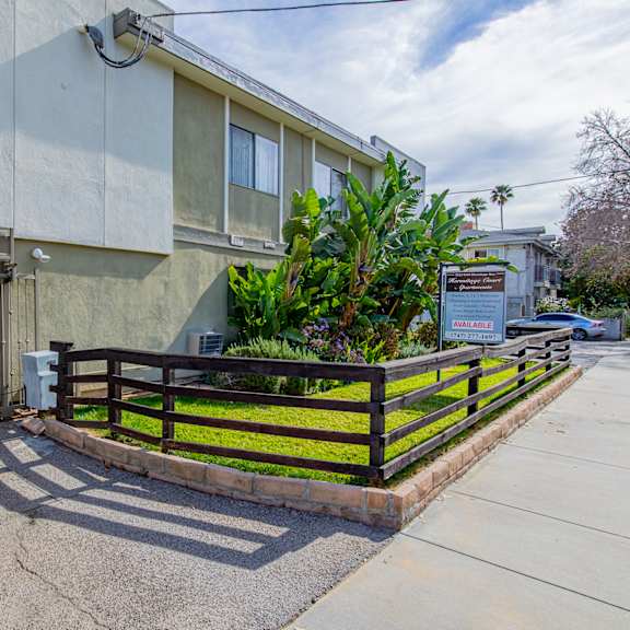 an apartment building with a fence and a sidewalk in front of it