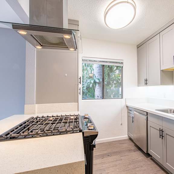an empty kitchen with stainless steel appliances and white cabinets