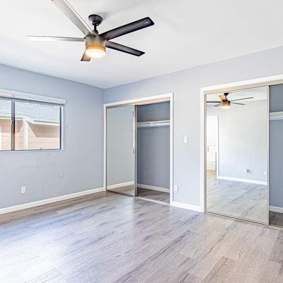 an empty living room with a ceiling fan and a mirror