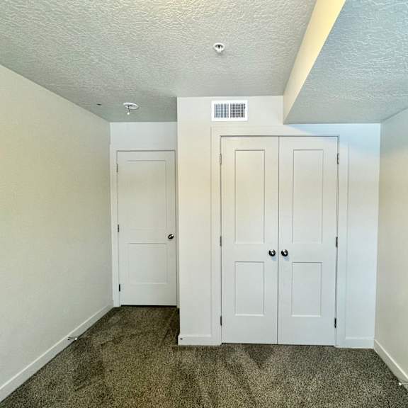 an empty bedroom with white closets and carpeted floors