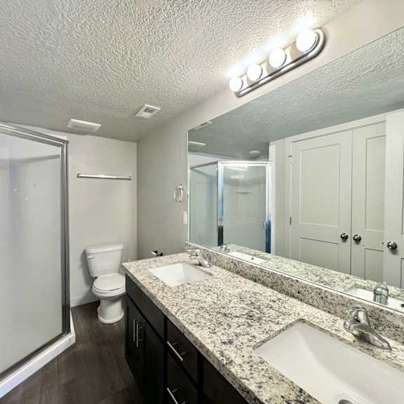 a bathroom with two sinks and a shower and a toilet