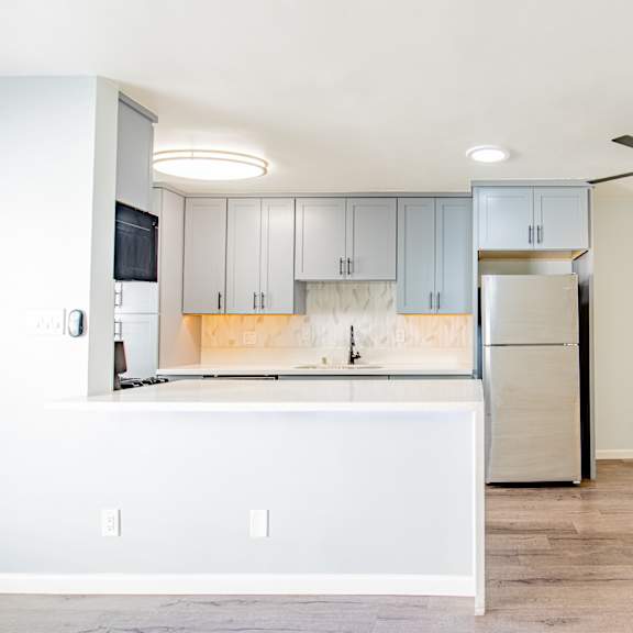 an empty kitchen with white cabinets and a refrigerator