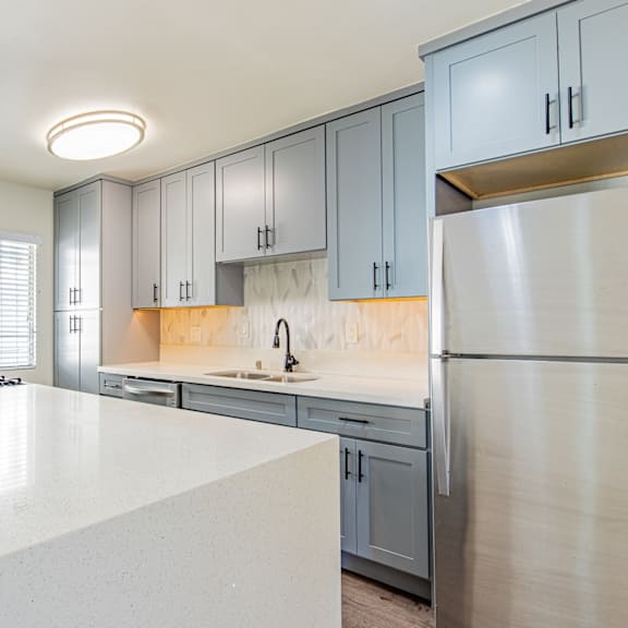 an empty kitchen with stainless steel appliances and white countertops