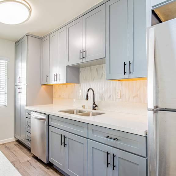 a kitchen with blue cabinets and a stainless steel refrigerator