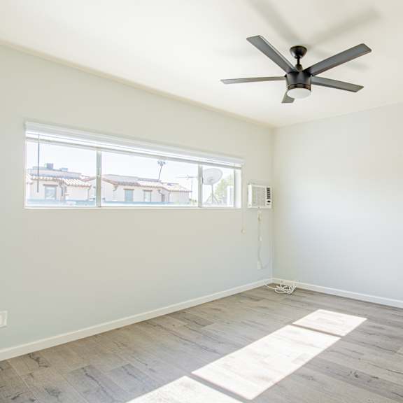 an empty room with a ceiling fan and a window